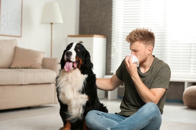 Photo of Young man suffering from fur allergy at home