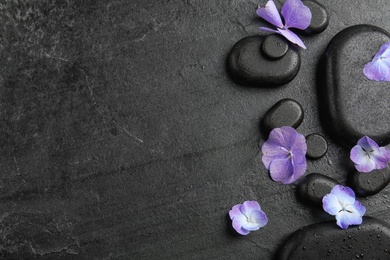 Photo of Zen stones and exotic flowers on dark background, top view with space for text