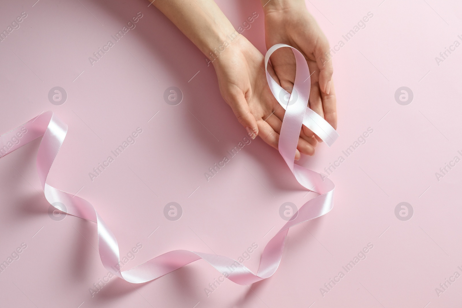 Photo of Woman holding pink ribbon on color background, top view. Breast cancer awareness