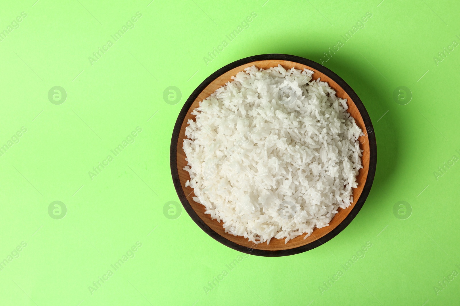 Photo of Bowl of boiled rice on color background, top view with space for text