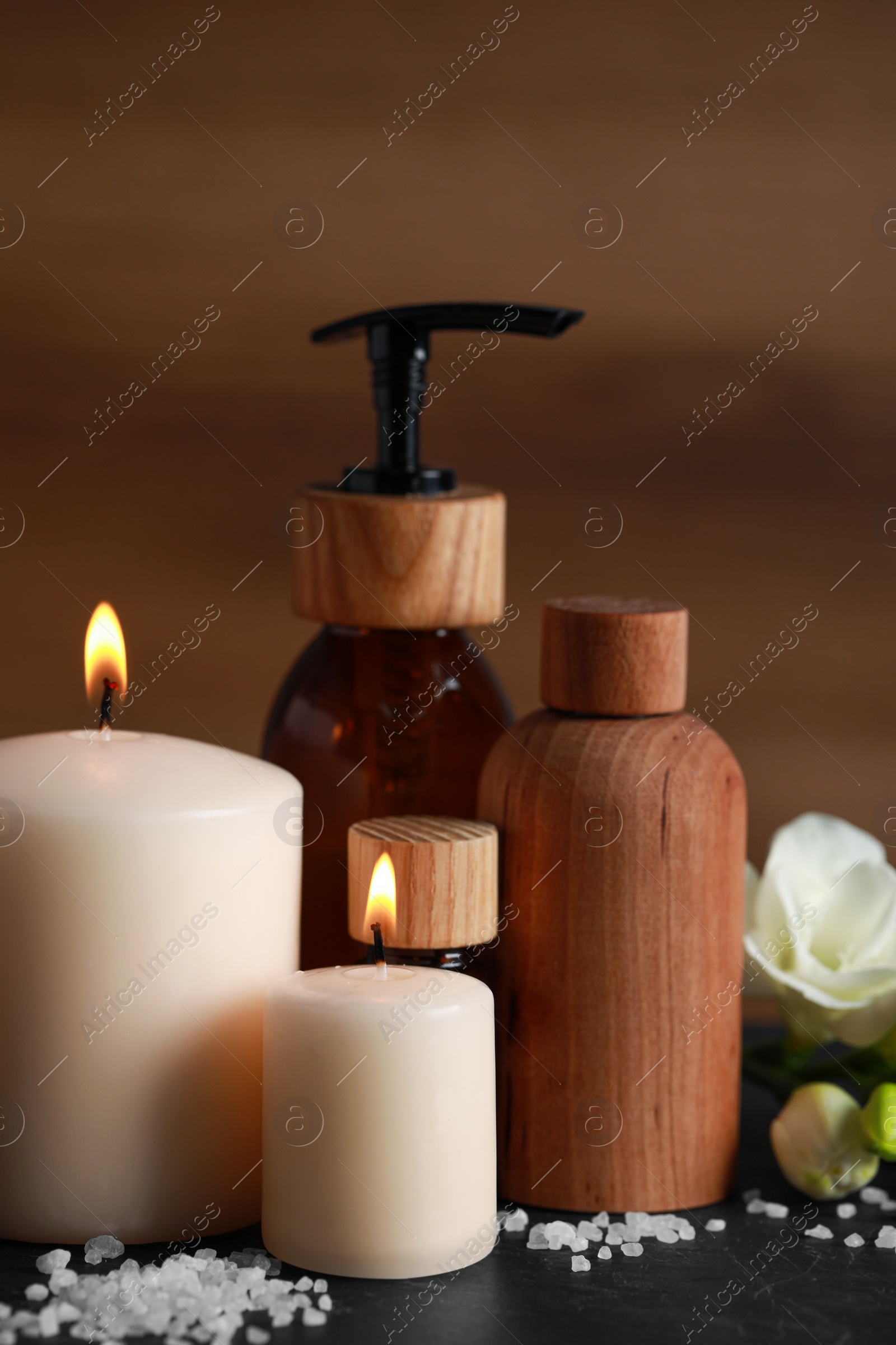 Photo of Beautiful spa composition with different care products and burning candles on black table