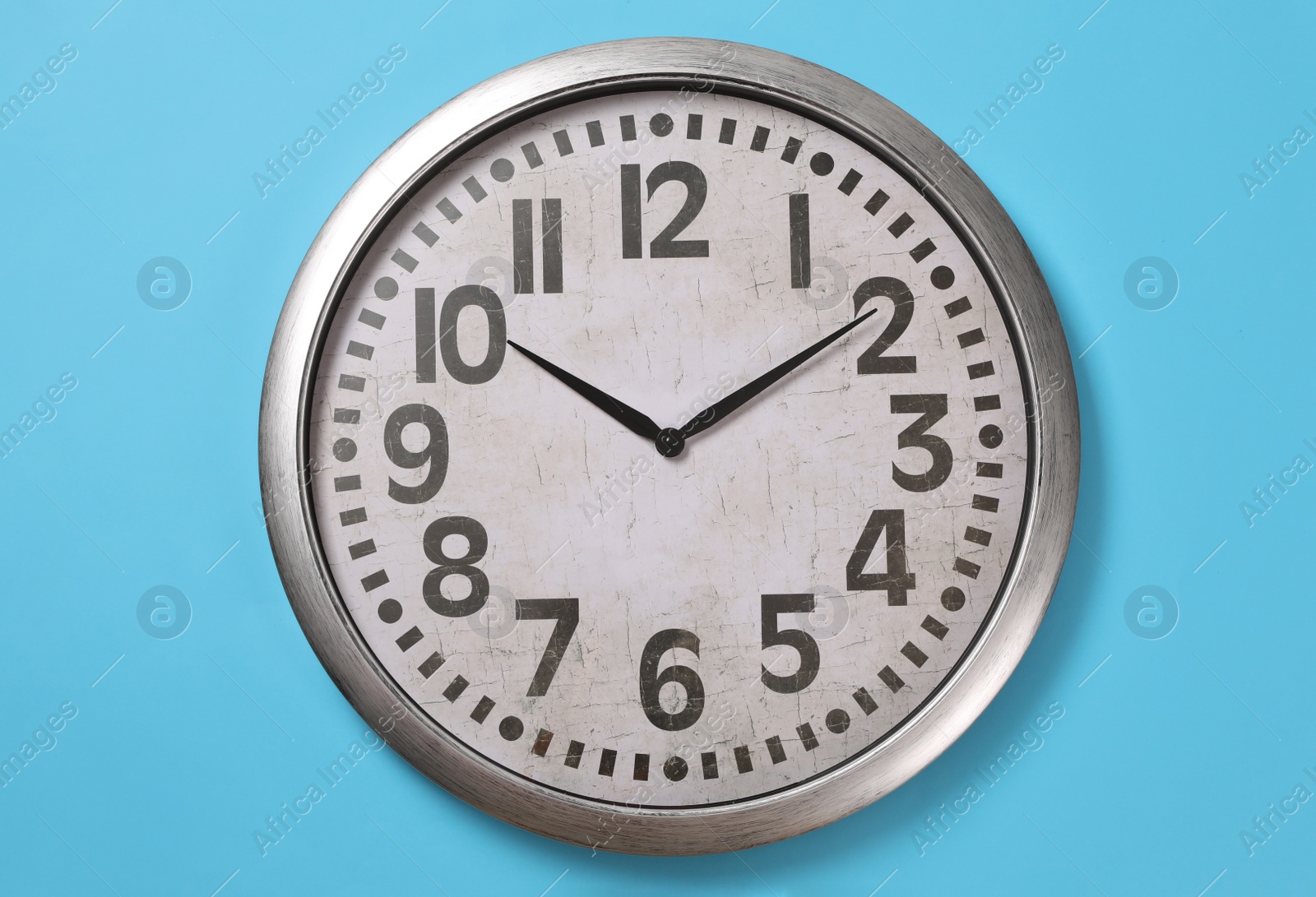 Photo of Stylish analog clock hanging on light blue wall