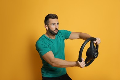Stressed man with steering wheel on yellow background