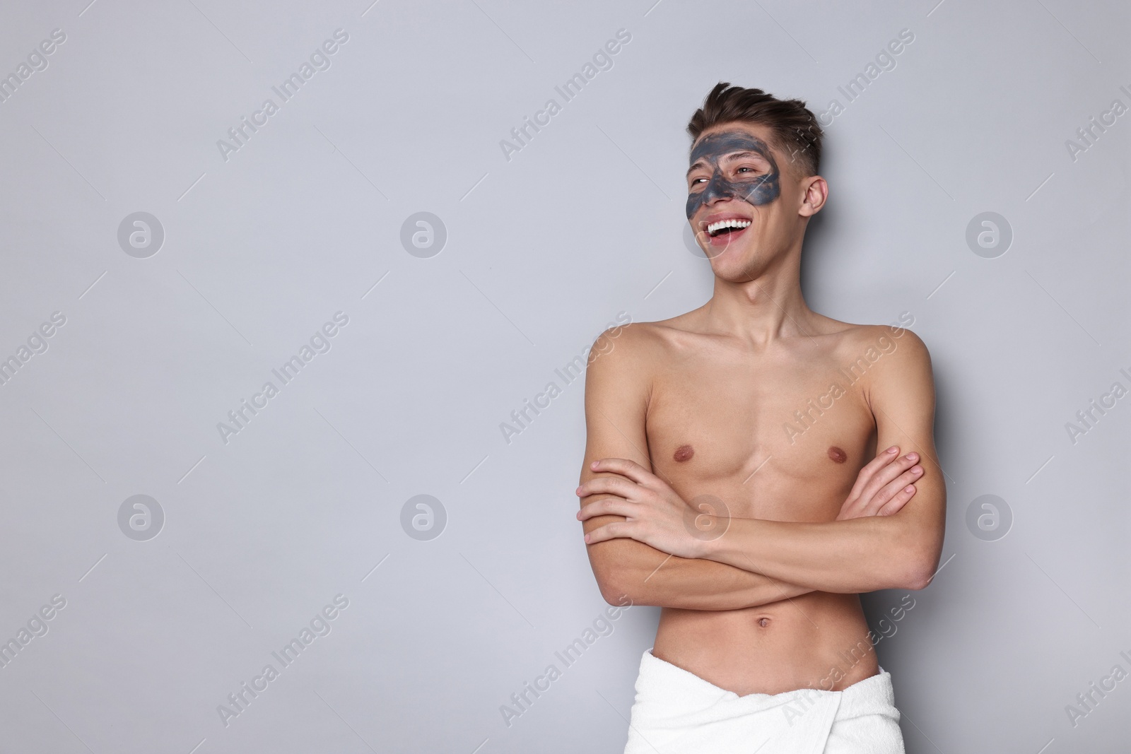 Photo of Handsome man with clay mask on his face against light grey background. Space for text