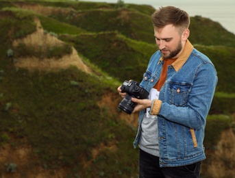 Photo of Male photographer with professional camera on green hill