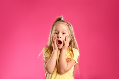 Photo of Portrait of shocked little girl on pink background