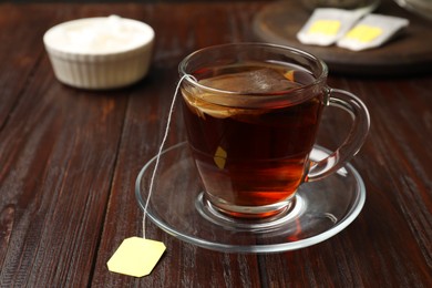 Brewing tea. Glass cup with tea bag on wooden table