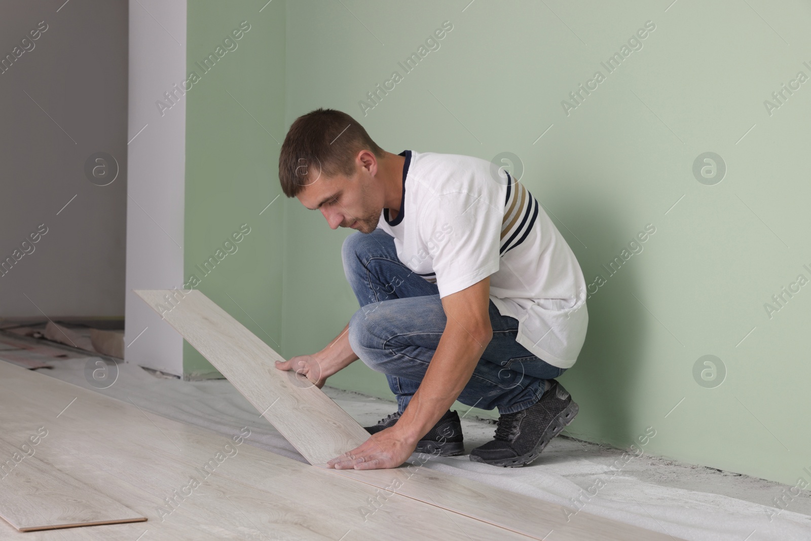 Photo of Man installing new laminate flooring in room