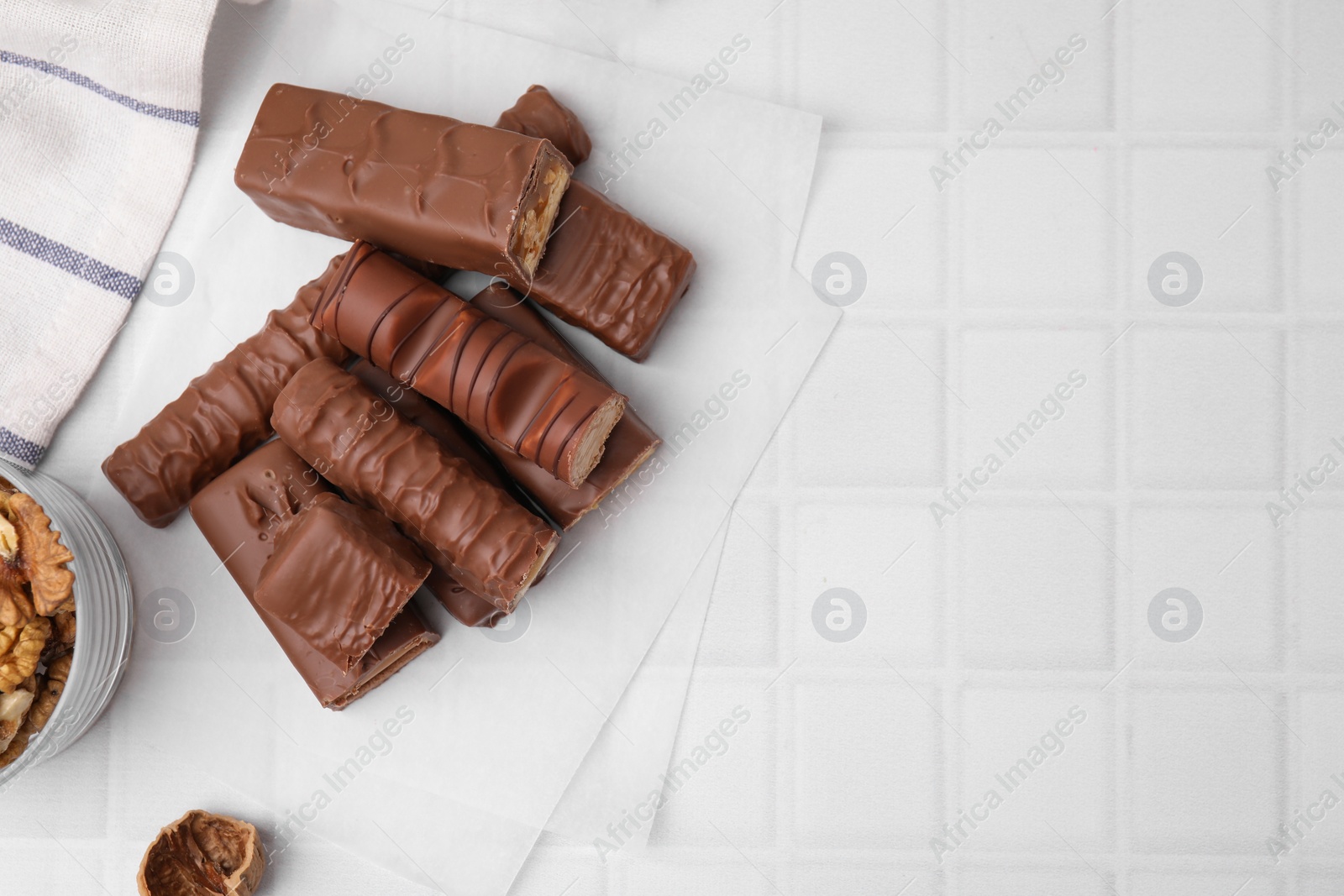 Photo of Different tasty chocolate bars on white tiled table, flat lay. Space for text