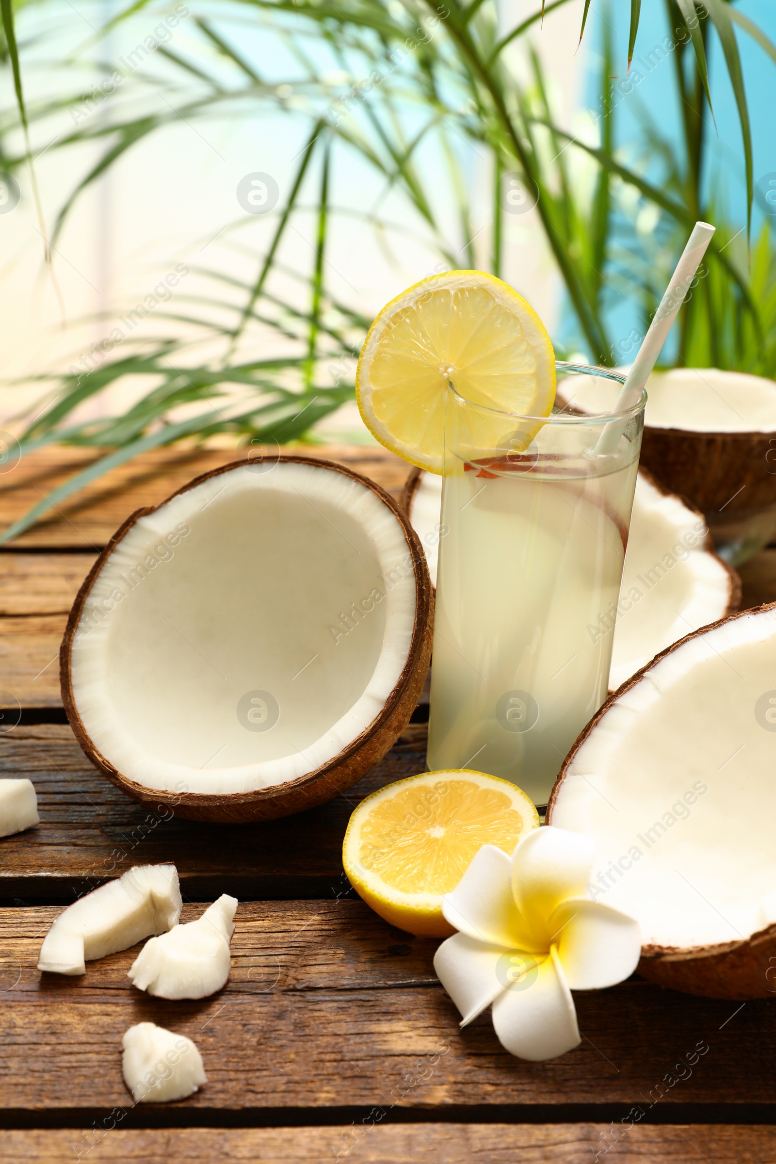 Photo of Composition with glass of coconut water and lemon on wooden table