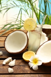 Photo of Composition with glass of coconut water and lemon on wooden table