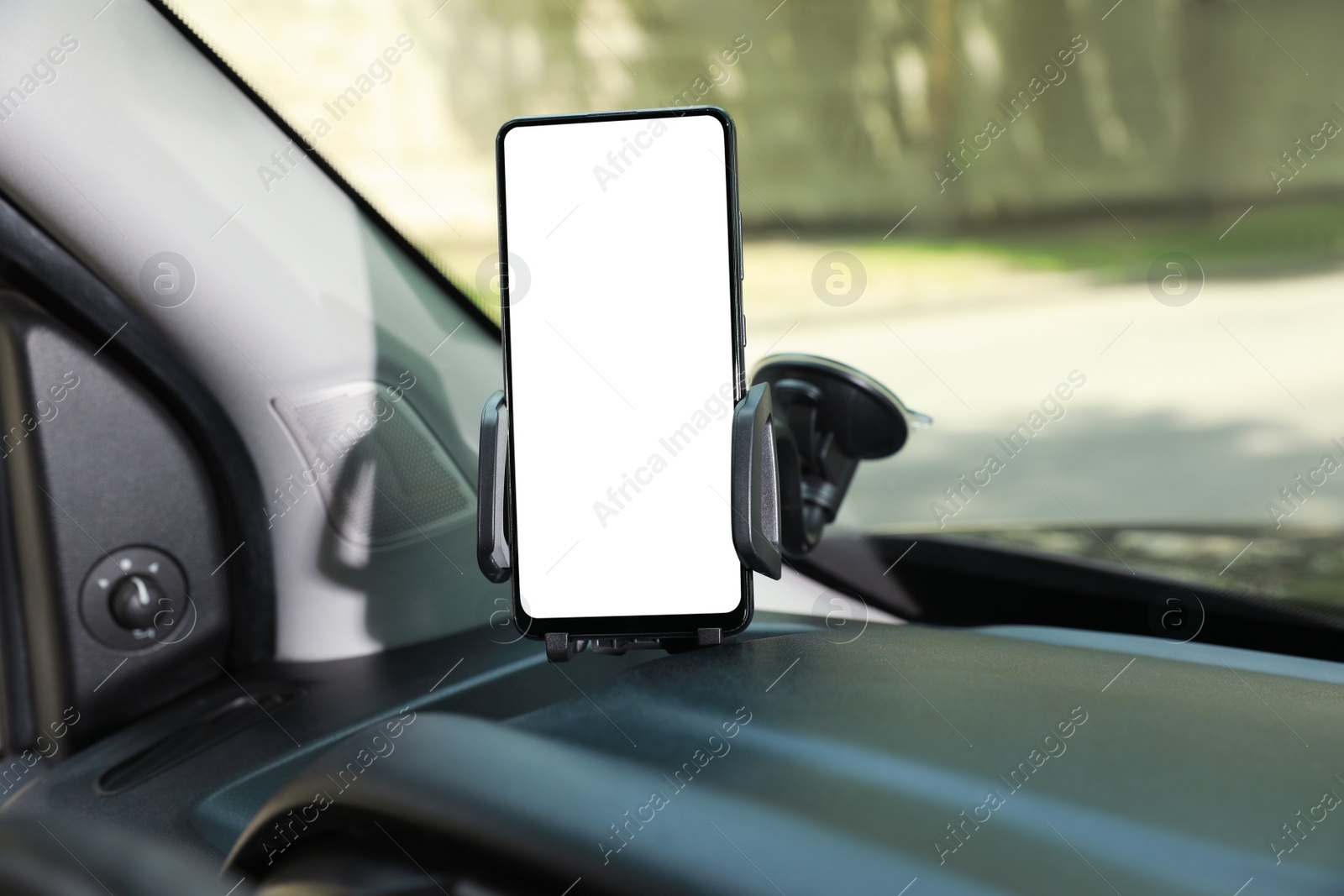 Photo of Car holder with modern mobile phone on windshield of automobile. Mockup for design