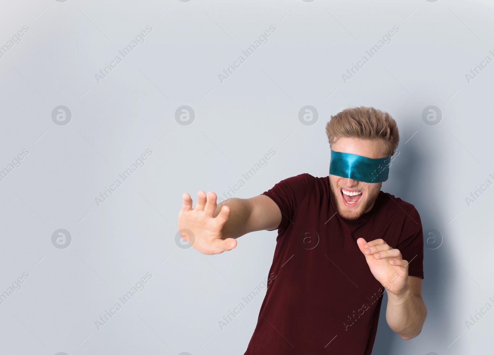 Photo of Young man wearing blue blindfold on light background