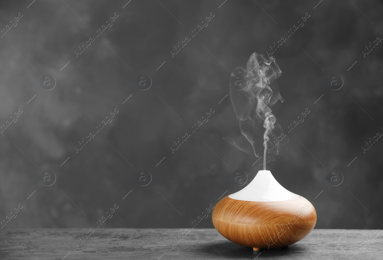 Photo of Aroma oil diffuser on table against grey background. Air freshener