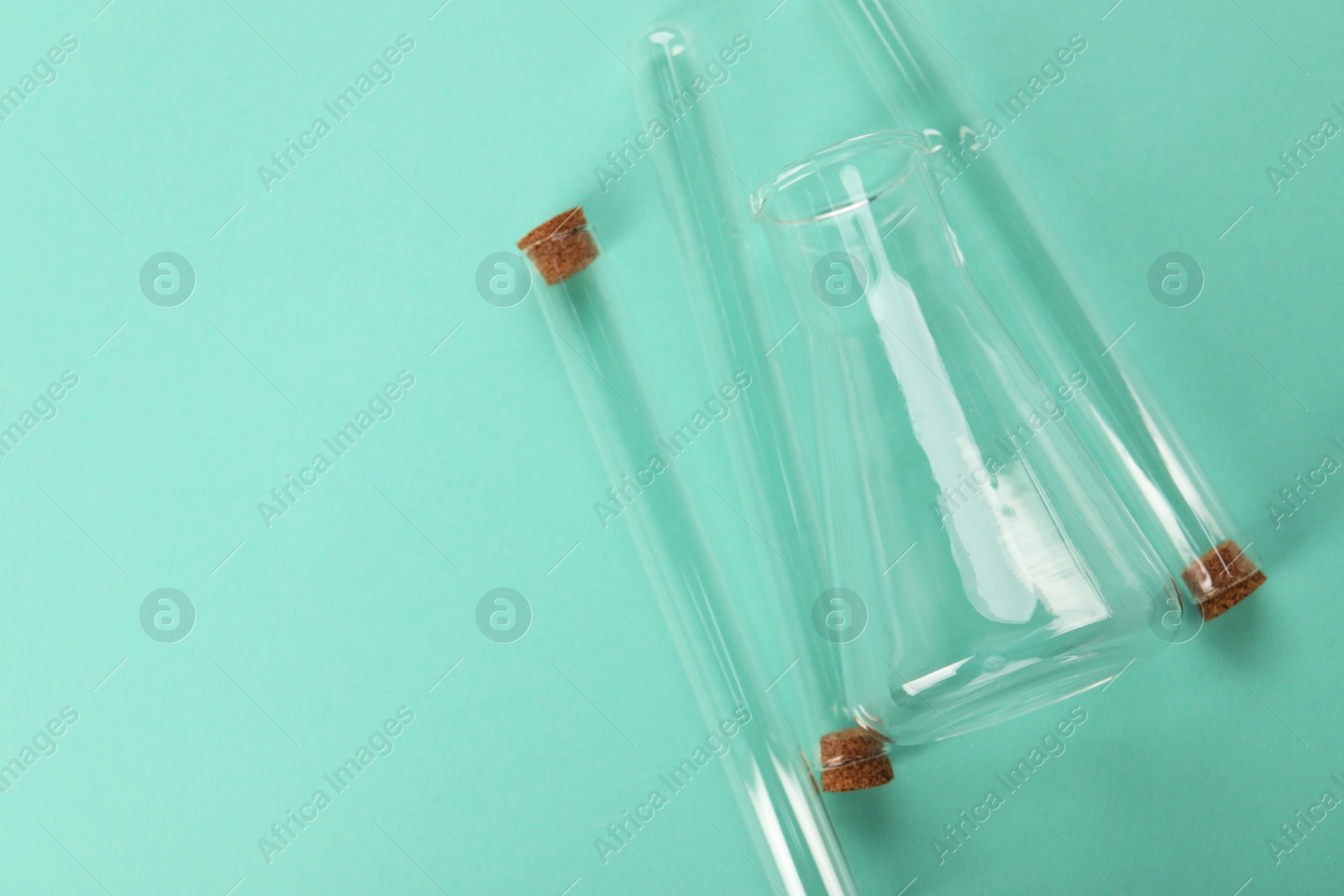 Photo of Flask and test tubes on turquoise background, flat lay with space for text. Laboratory glassware