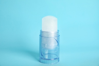 Photo of Natural crystal alum stick deodorant on light blue background