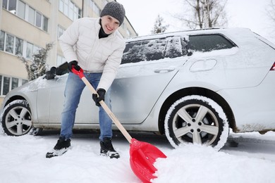 Photo of Man removing snow with shovel near car outdoors, low angle view