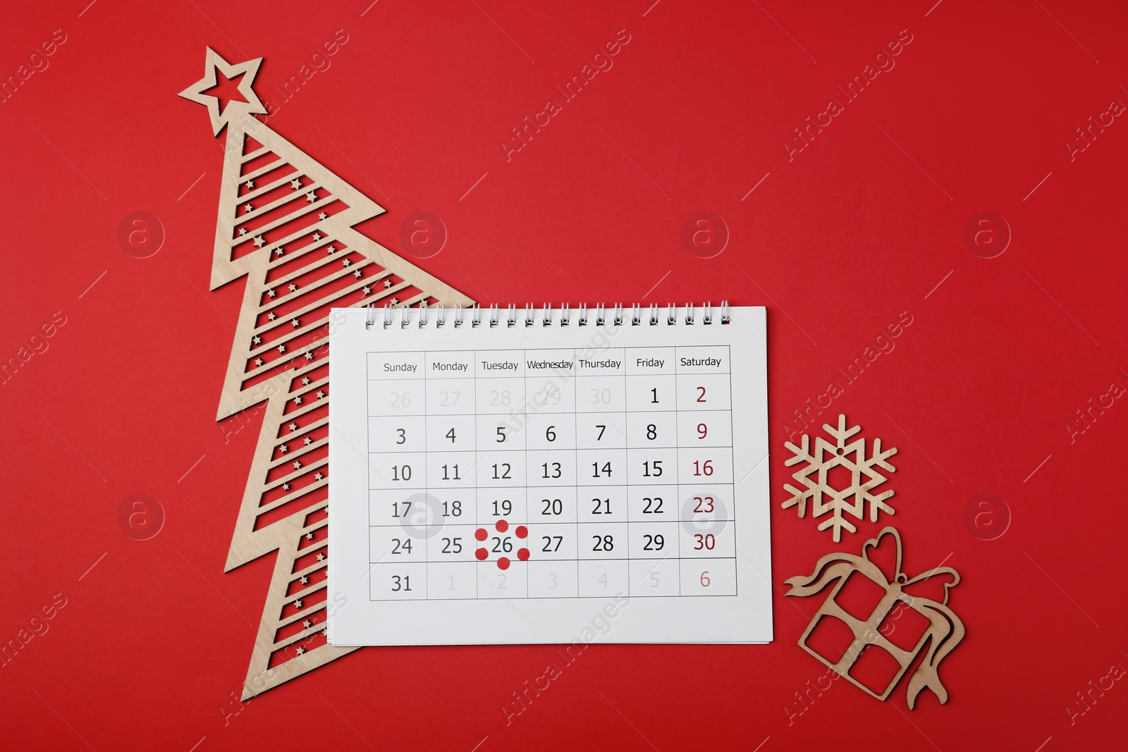 Photo of Calendar with marked Boxing Day date and Christmas decorations on red background, flat lay