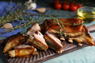 Photo of Delicious roasted ribs served on light blue wooden table, closeup
