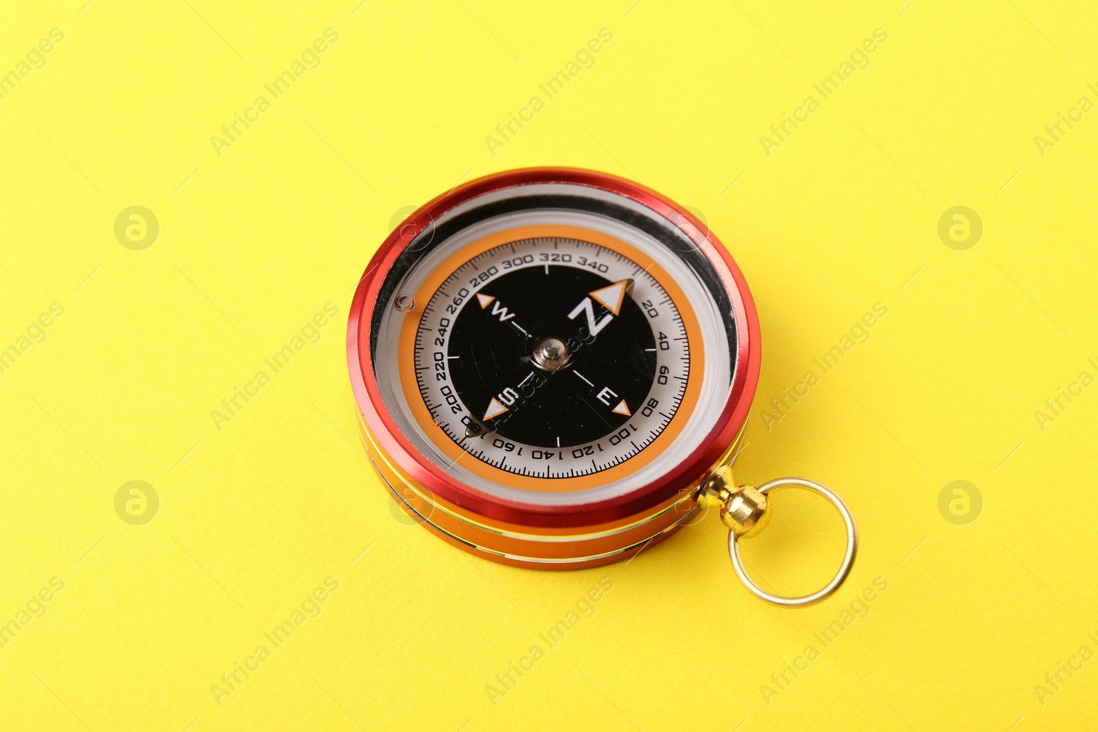 Photo of One compass on yellow background. Navigation equipment