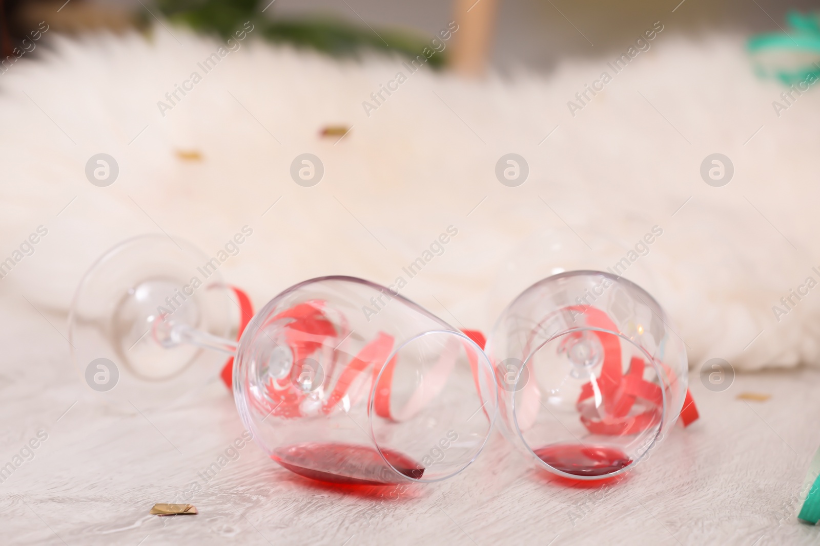 Photo of Overturned wineglasses on messy floor indoors. After party chaos