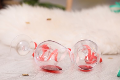 Photo of Overturned wineglasses on messy floor indoors. After party chaos