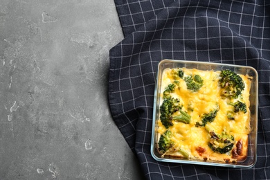 Photo of Tasty broccoli casserole in baking dish on grey table, top view. Space for text