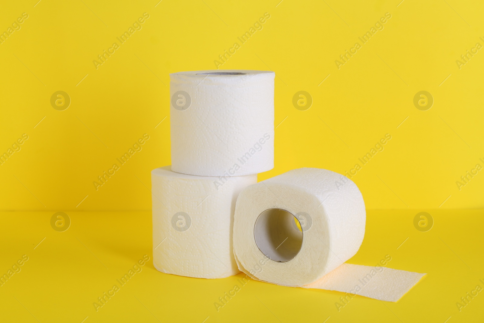 Photo of Many soft toilet paper rolls on yellow background