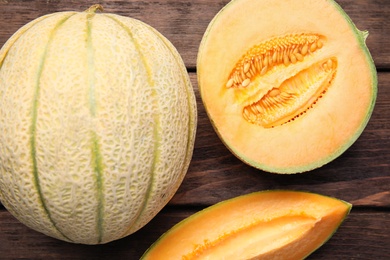 Photo of Tasty fresh melons on wooden table, flat lay