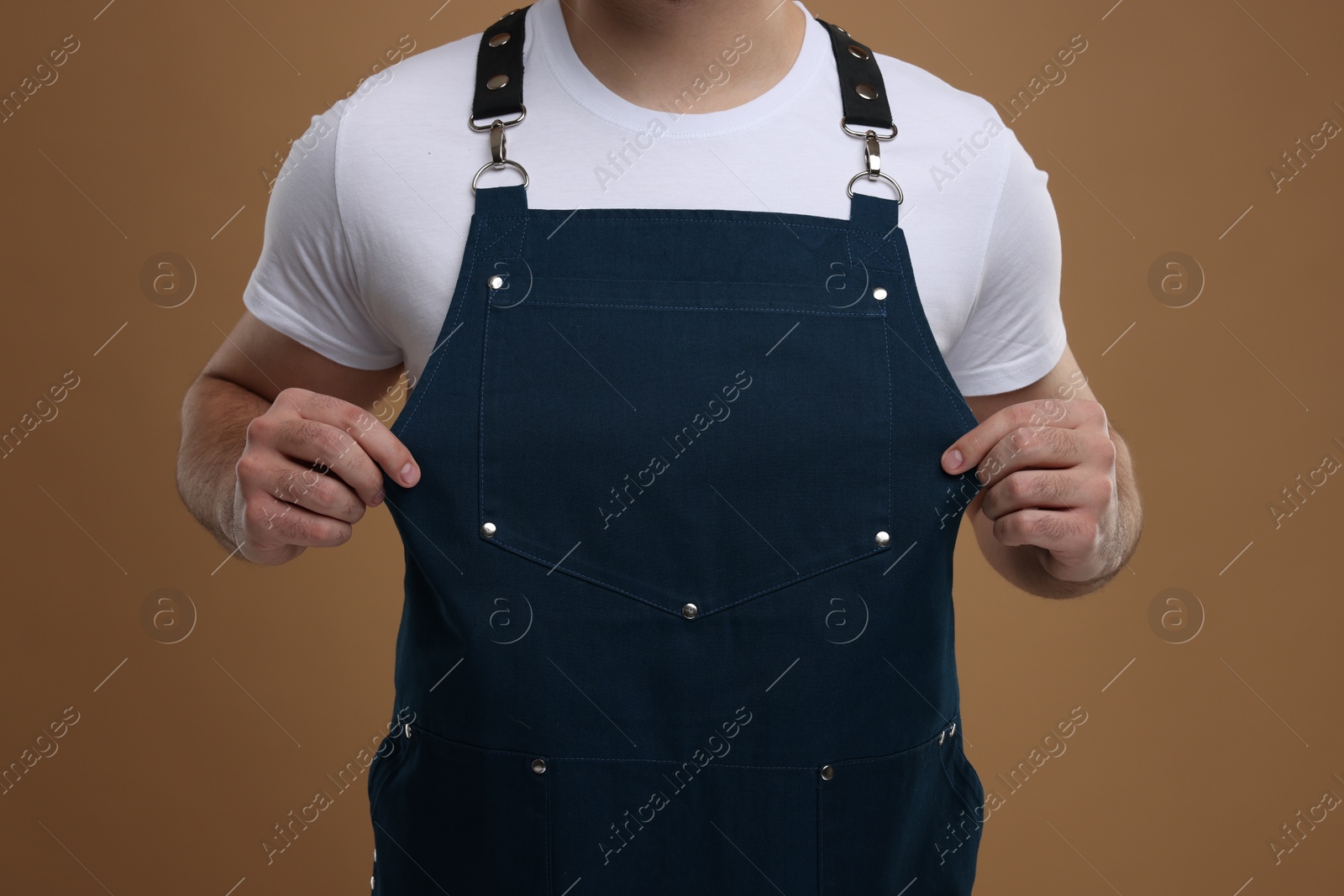 Photo of Man in kitchen apron on brown background, closeup. Mockup for design