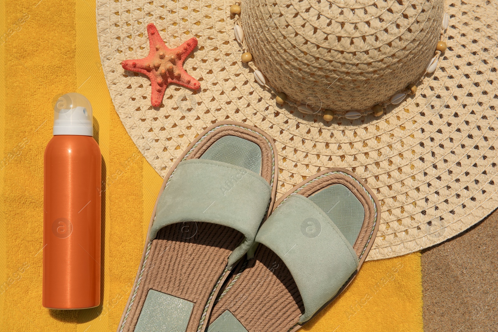 Photo of Sunscreen, slides and hat on beach towel, top view. Sun protection care