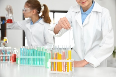 Photo of Smart pupil making experiment in chemistry class, closeup