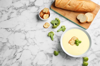 Photo of Flat lay composition with bowl of cheese cream soup and broccoli on white marble table, space for text
