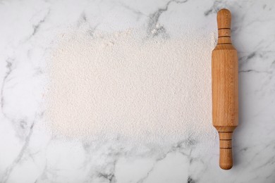 Photo of Frame made of flour and rolling pin on white marble table, top view. Space for text