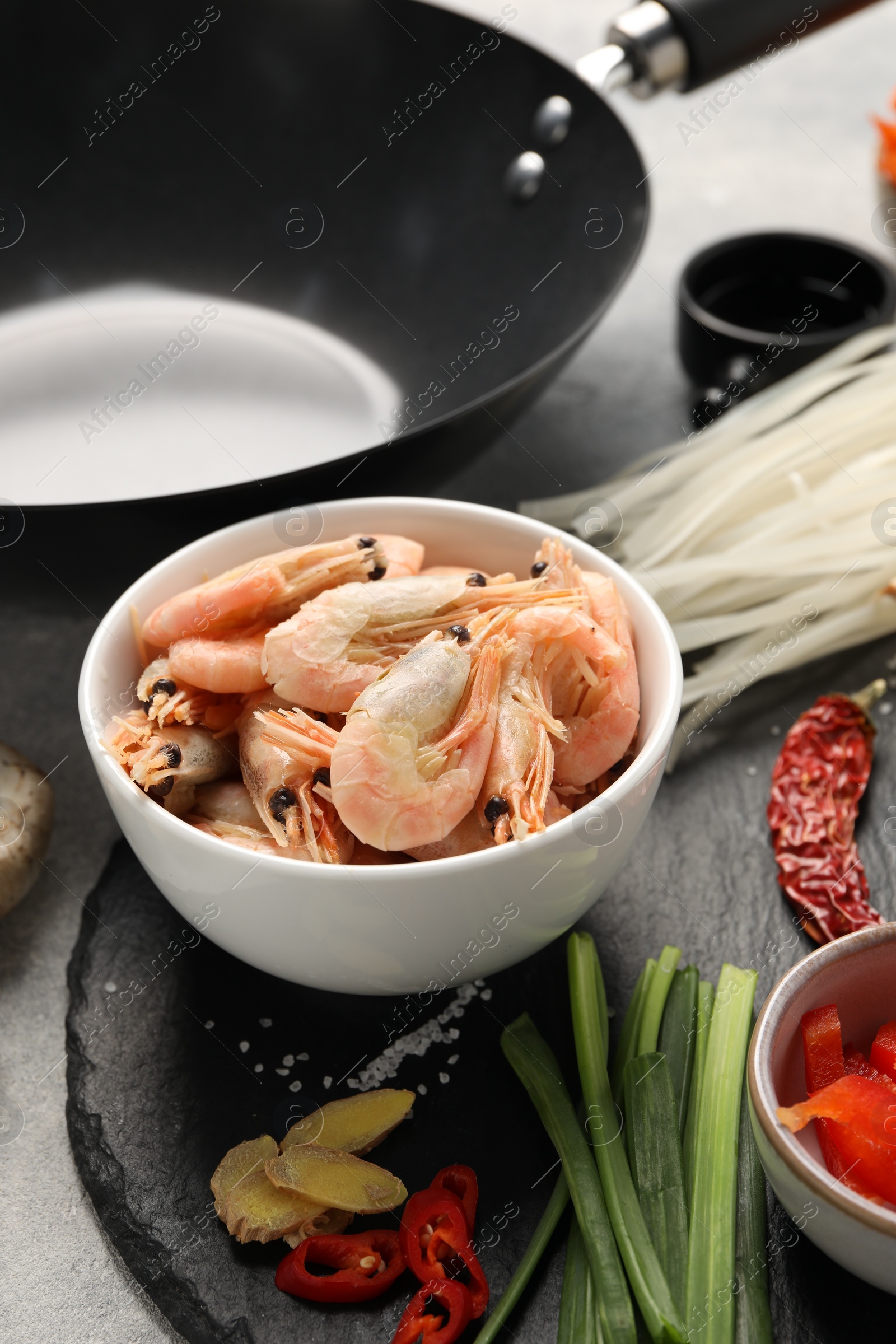 Photo of Different products and black wok on grey table, closeup