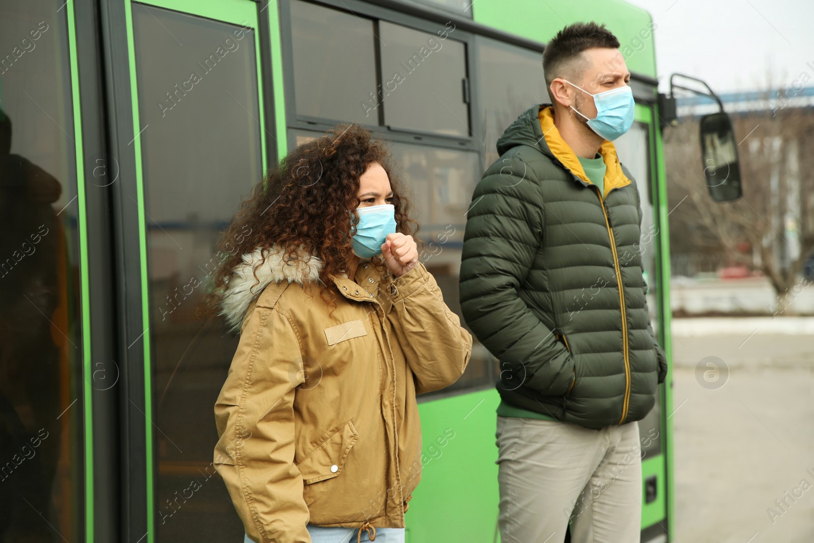 Photo of People with disposable masks near bus outdoors. Virus protection