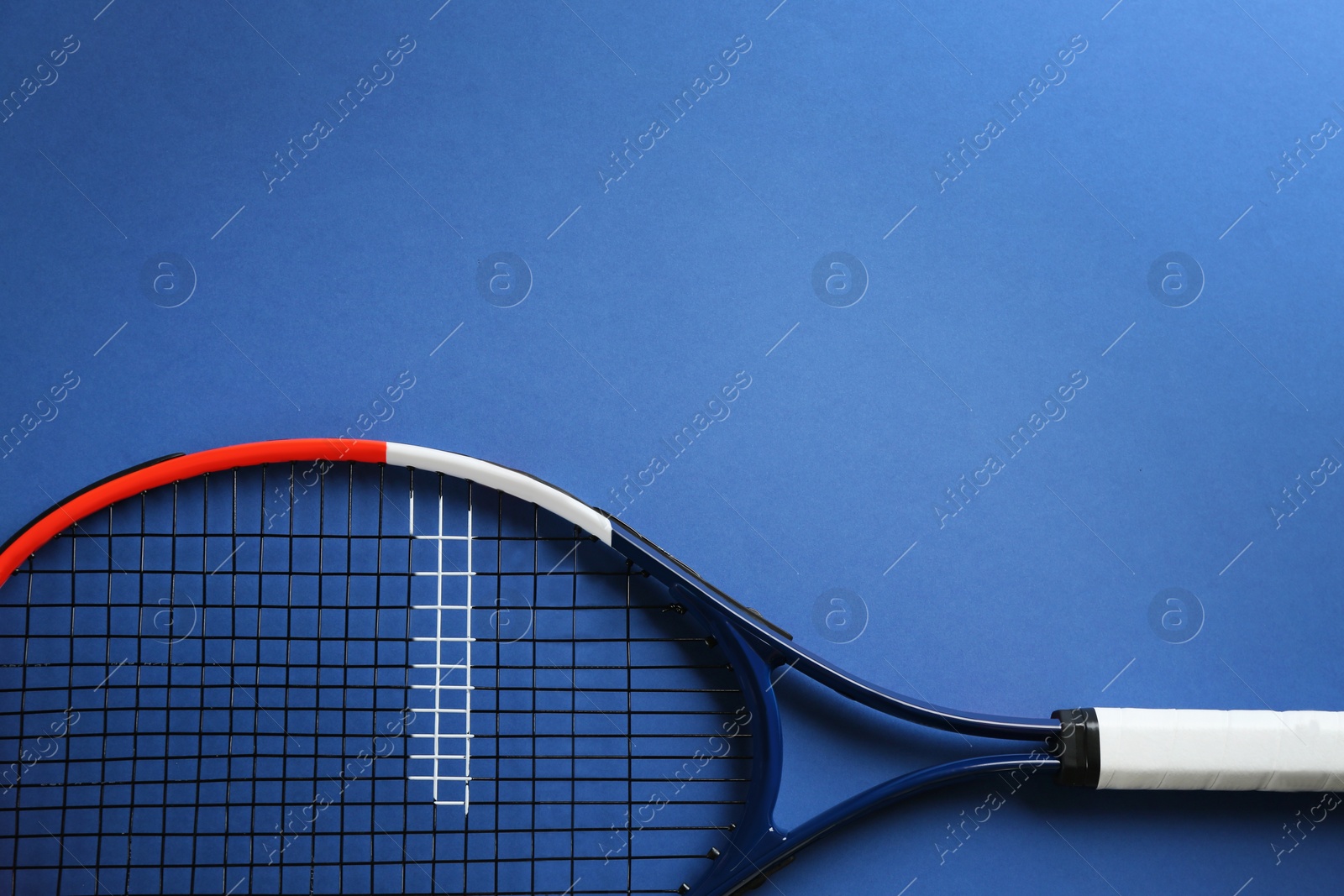 Photo of Tennis racket on blue background, top view. Space for text