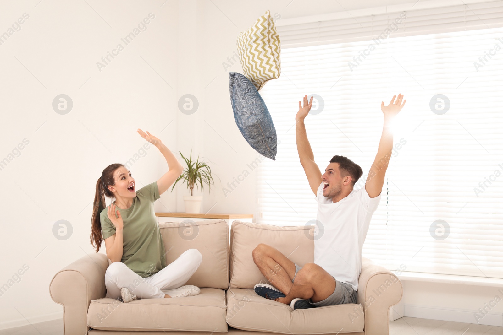 Photo of Happy couple having pillow fight in living room