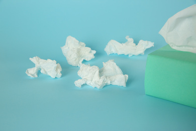 Photo of Used paper tissues and box on light blue background