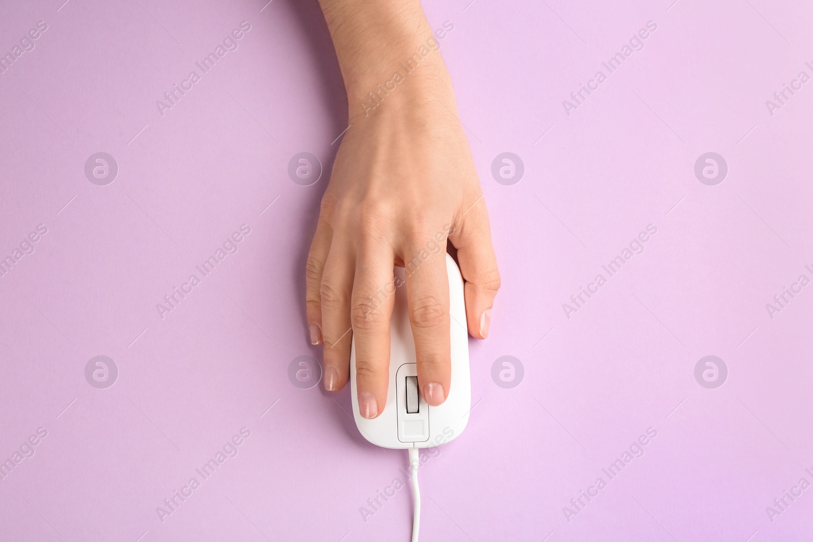 Photo of Woman using modern wired optical mouse on lilac background, top view