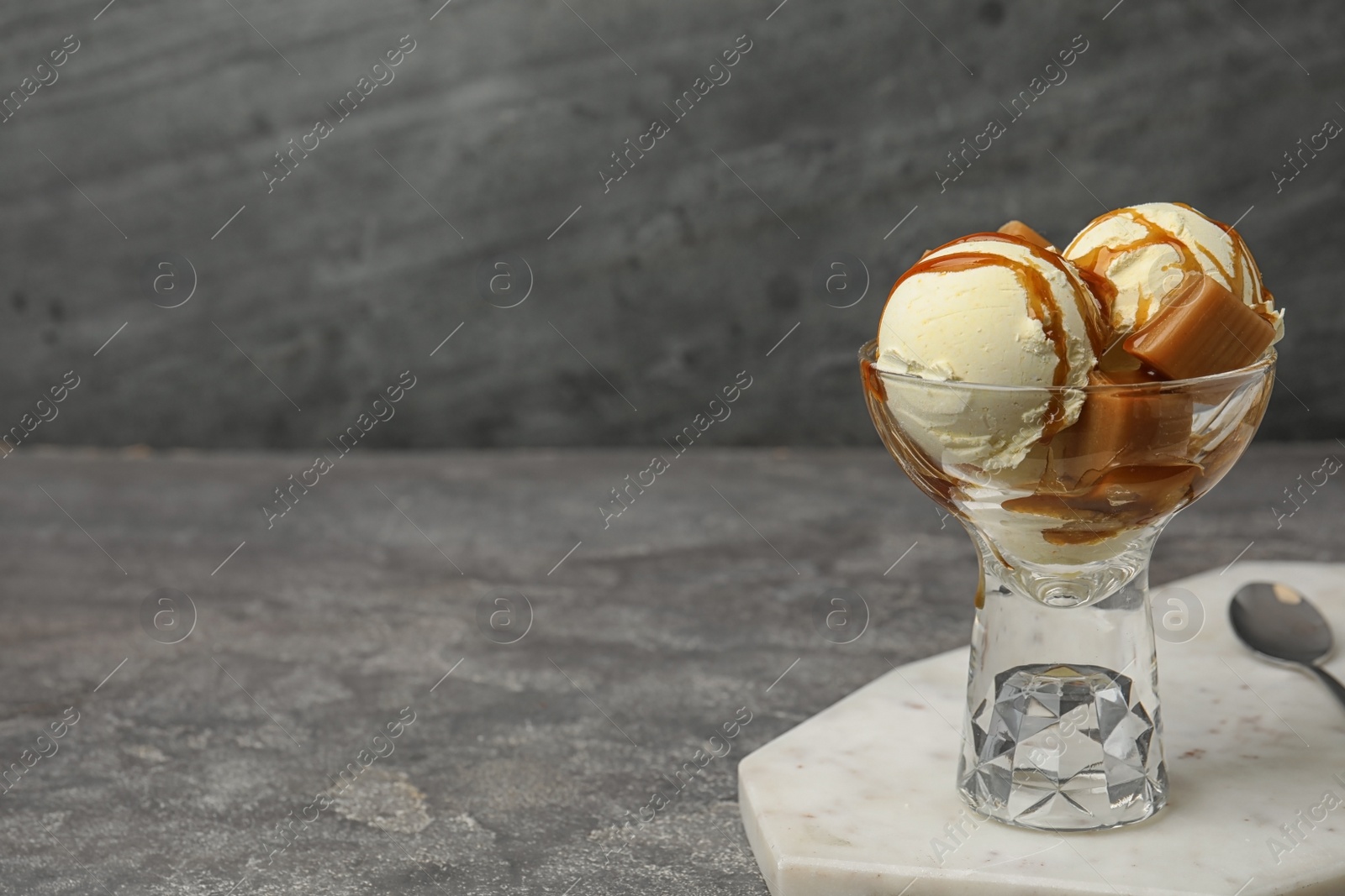 Photo of Delicious ice cream with caramel and sauce served on table. Space for text