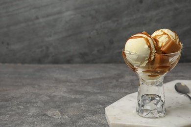Delicious ice cream with caramel and sauce served on table. Space for text