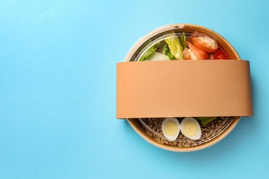 Photo of Tasty food in container on light blue background, top view. Space for text