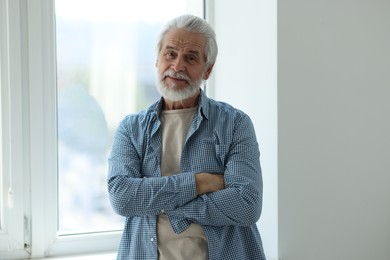 Photo of Portrait of happy grandpa with grey hair near window indoors