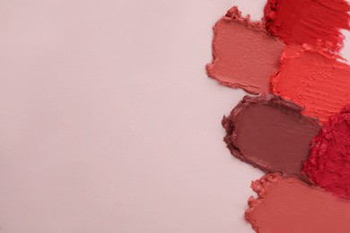 Smears of different beautiful lipsticks on light background, top view. Space for text
