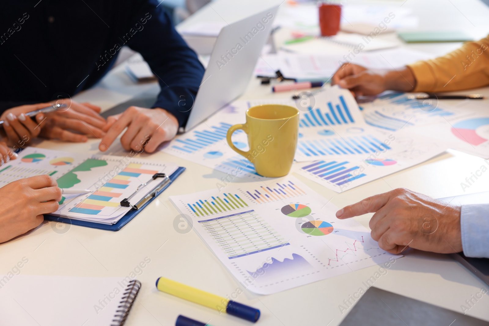 Photo of Team of employees working with charts at table, closeup. Startup project