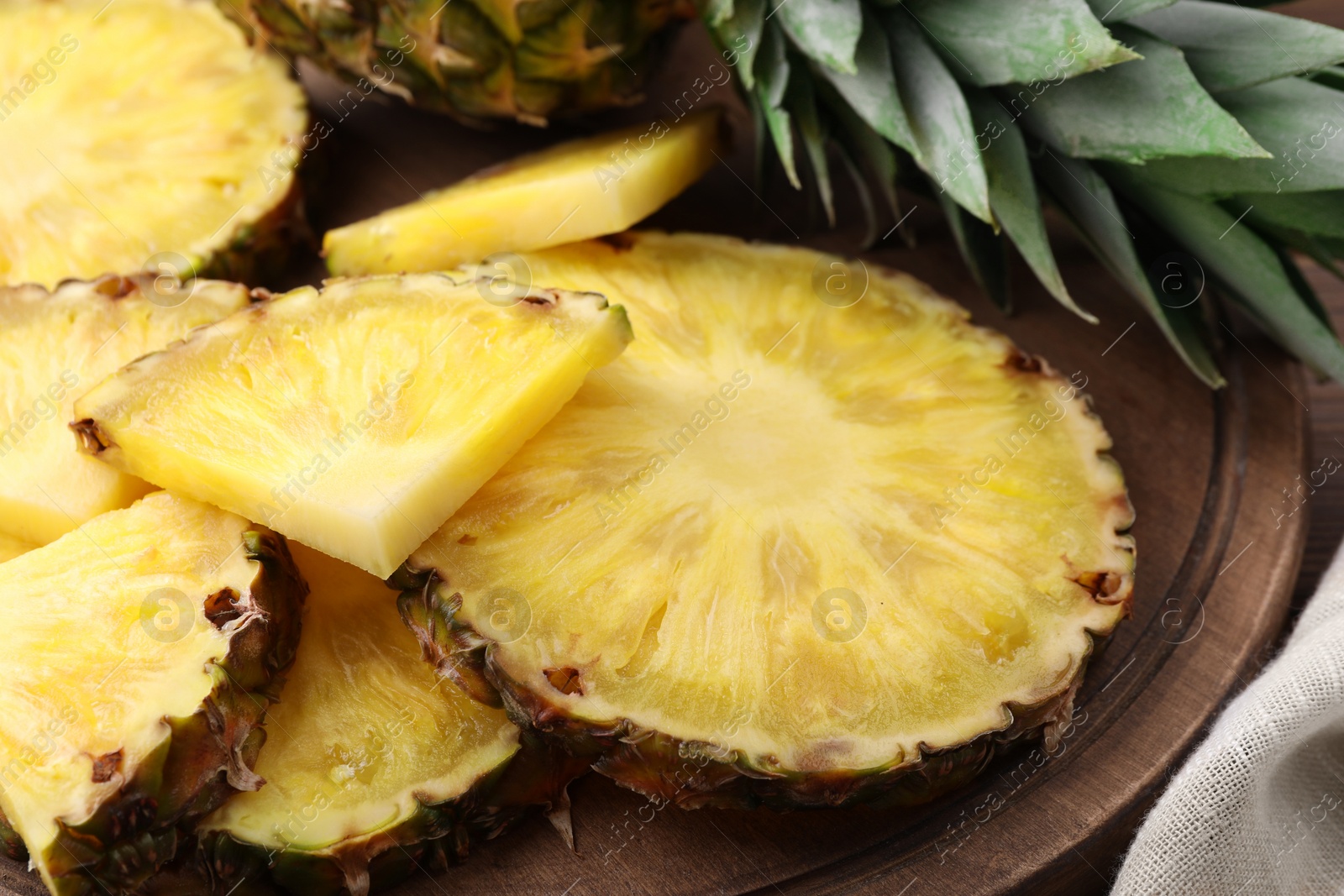 Photo of Pieces of tasty ripe pineapple on wooden board, closeup
