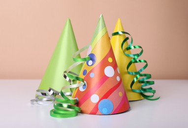 Colorful party hats and streamers on white table. Birthday celebration