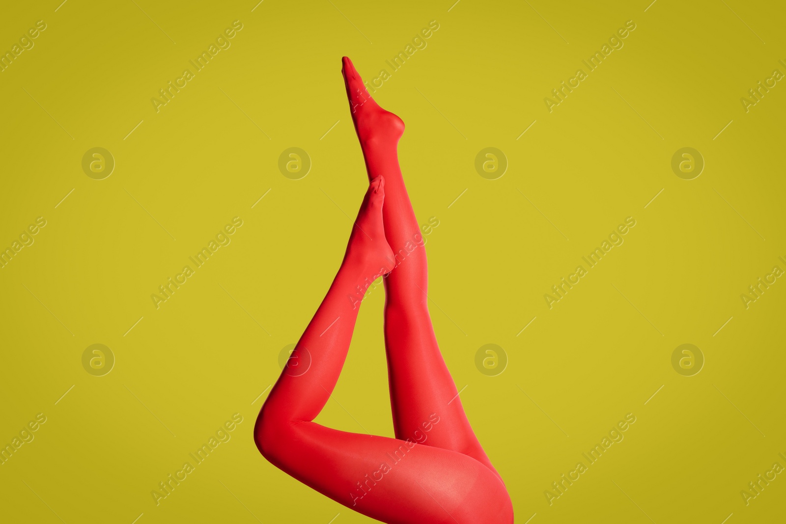 Photo of Woman wearing red tights on yellow background, closeup of legs