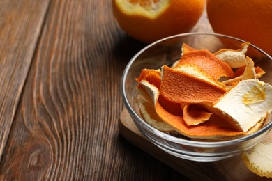 Photo of Dry orange peels on wooden table, closeup. Space for text